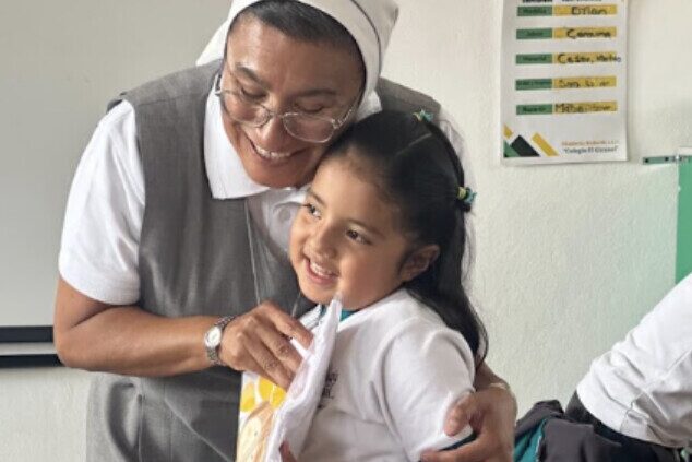 Una hermana abraza sonriendo a una niña en un salón del Colegio El Girasol.