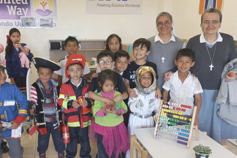 Dos hermanas posan con un grupo de niños disfrazados de bombero, pirata y astronauta en un aula de Mariana Sala I.A.P.